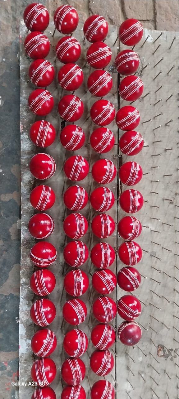 Red cricket balls held in pin racks during finishing stage at GEO SPORTS Meerut