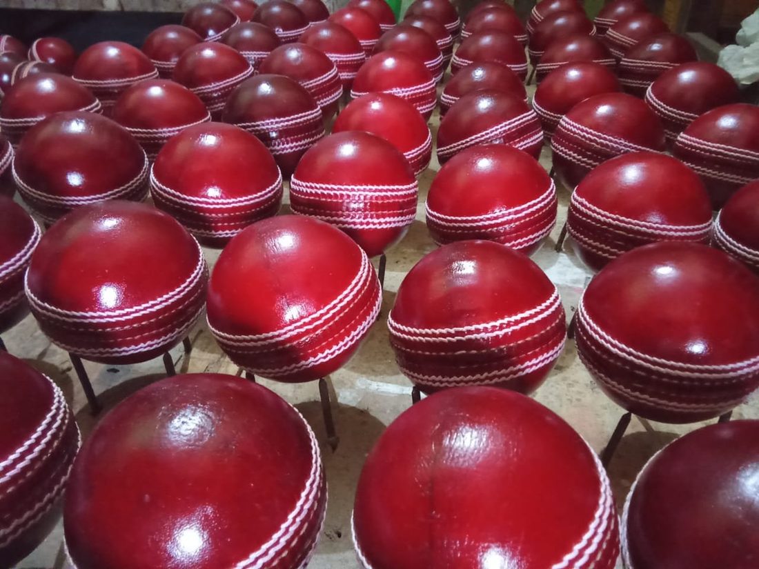 Batch of finished red cricket balls lined up for quality inspection at GEO SPORTS workshop