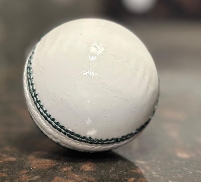 White cricket ball with green seam